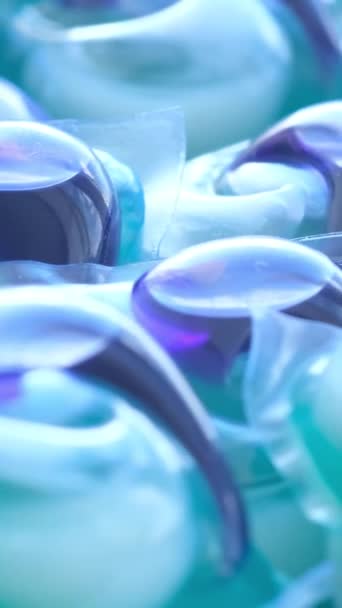 Blue capsules for washing clothes in an automatic machine. The concept of washing clothes. Vertical video. - Footage, Video