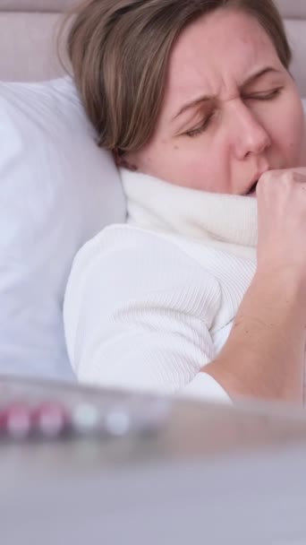 Naisella on flunssa. Kurkkukipu, yskä ja kuume. Vilustuminen, yskä. Pystysuora video - Materiaali, video