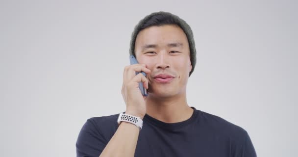 Telefonní hovor, úsměv a asijský muž s rozhovorem, kontakt a diskuse na bílém pozadí studia. Japonská osoba, komunikace a model s mobilním telefonem, chatování a síť s internetem. - Záběry, video