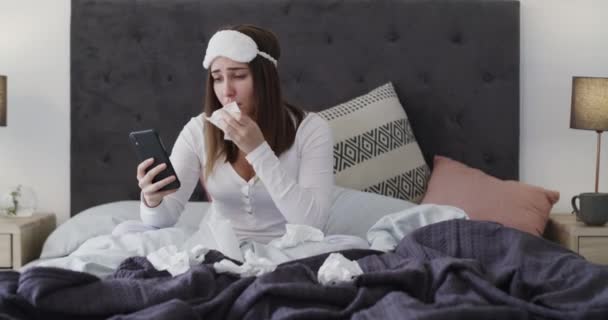 Τηλέφωνο, κλάμα και γυναίκα με χαρτομάντιλα στο κρεβάτι να διαβάζει μήνυμα για χωρισμό στο διαμέρισμά της. Τεχνολογία, κατάθλιψη και λυπημένη νεαρή γυναίκα κουβεντιάζοντας για διαζύγιο στο κινητό τηλέφωνο στο σύγχρονο σπίτι - Πλάνα, βίντεο