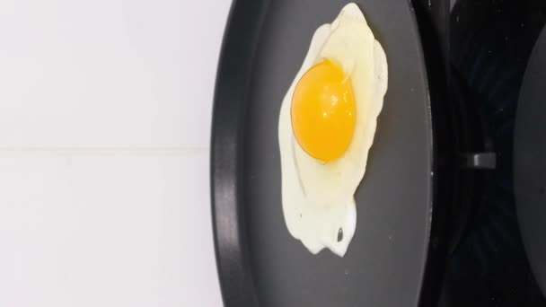 Cuire un œuf dans une casserole. Cuisiner. Œuf frit. Vidéo verticale. - Séquence, vidéo