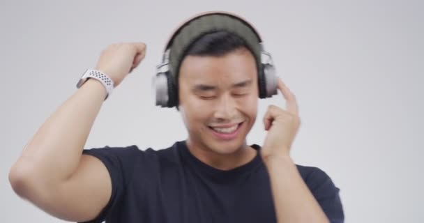 Asijský muž, sluchátka a tanec na hudbu pro studenty wellness, streaming služby a kpop píseň ve studiu. Mladý korejský člověk se zvukem, elektronikou a nasloucháním s energií na bílém pozadí. - Záběry, video