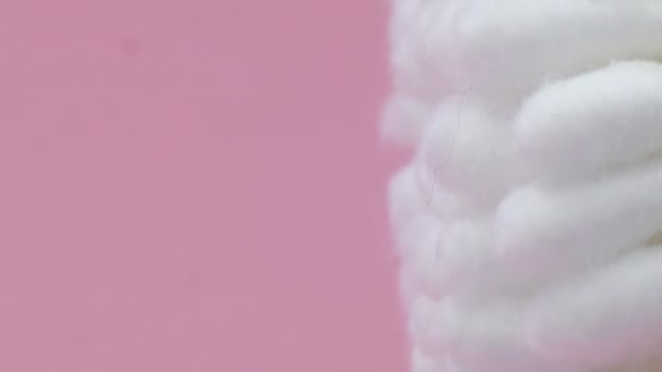 Βαμβακερά επιχρίσματα λευκού χρώματος περιστρέφονται σε κύκλο σε ροζ φόντο. Κάθετη βίντεο. - Πλάνα, βίντεο