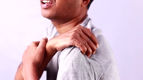 Un hombre indio sufriendo de dolor de hombro mostrando expresión dolorosa sobre fondo blanco - Imágenes, Vídeo