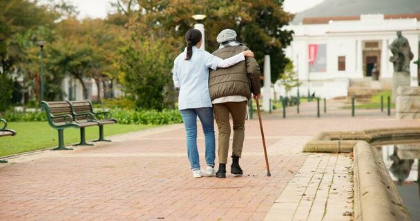 Nurse, relax and park with old woman and walking stick for retirement, elderly care and physical therapy. Trust, medical and healthcare with senior patient and caregiver in nature for rehabilitation. - Photo, Image