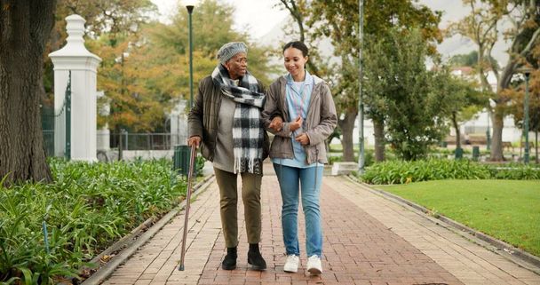 Pomoc, trzcina i pielęgniarka ze starą kobietą w parku na relaks, wsparcie i osoby niepełnosprawne. Opieka nad osobami starszymi, rozmowa i opieka zdrowotna z opiekunem i pacjentem w charakterze rehabilitacji medycznej. - Zdjęcie, obraz
