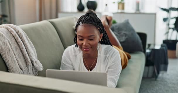 Schwarze Frau auf dem Sofa, entspannen oder tippen auf dem Laptop für die Fernarbeit, soziale Medien oder Blog-Post Forschung mit Lächeln zu Hause. Glückliches Mädchen auf dem Sofa mit Computer E-Mail, Website oder Online-Chat im Haus. - Filmmaterial, Video