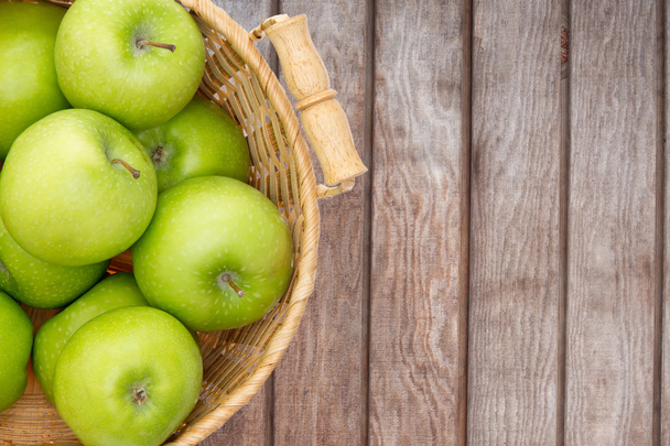 Wicker basket of crisp green apples - Фото, зображення