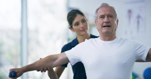 Fyzioterapie, činorodec a starší muž dělá cvičení paže, rehabilitace a poradenství o zdravotním pokroku. Fyzioterapeut, konzultace se zdravotní péčí a žena pomáhá seniorské klientce. - Záběry, video
