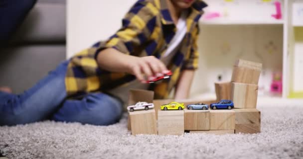 Toy cars, child and building blocks on carpet in living room, youth happiness and park vehicle game in family home. Young boy, floor or sportscar fantasy, freedom and summer holiday to relax in house. - Footage, Video