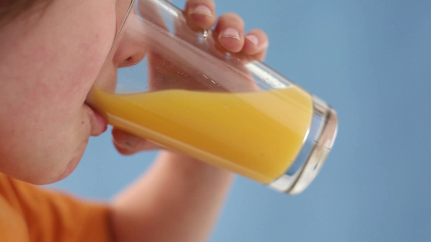 Boy drinking orange juice - Materiał filmowy, wideo