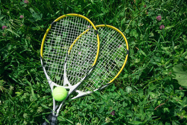Теннисный мяч и ракетка на зеленом фоне травы. - Фото, изображение
