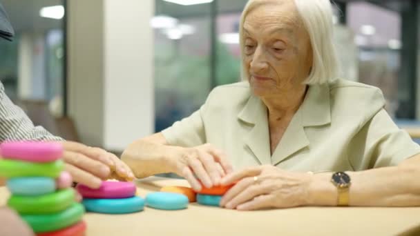 Видео пожилой женщины, играющей в игры с круглыми фигурами в гериатрии - Кадры, видео