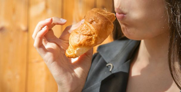 Mujer joven caucásica comiendo croissant. - Foto, Imagen