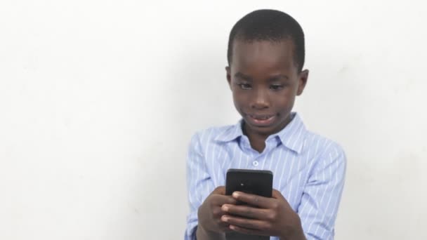 Niño pequeño sosteniendo un teléfono móvil y mirarlo con sonrisa. - Imágenes, Vídeo