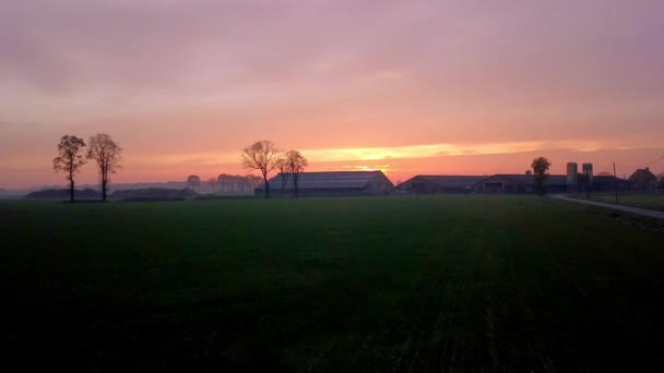 Questo suggestivo filmato cattura il calore e la tranquillità di un tramonto che scende su un paesaggio rurale agricolo. Alberi sagomati e un casale contro la luce sbiadita del giorno creano un - Filmati, video