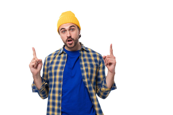 pohledný mladý hipster muž v čepici a košili gestikulující aktivně na bílém pozadí s kopírovacím prostorem. - Fotografie, Obrázek