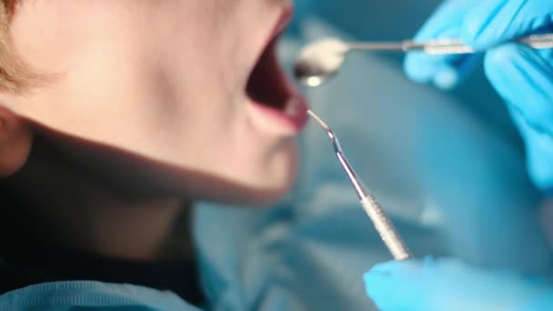 zubař vyšetřující chlapecké zuby zubními nástroji  - Záběry, video