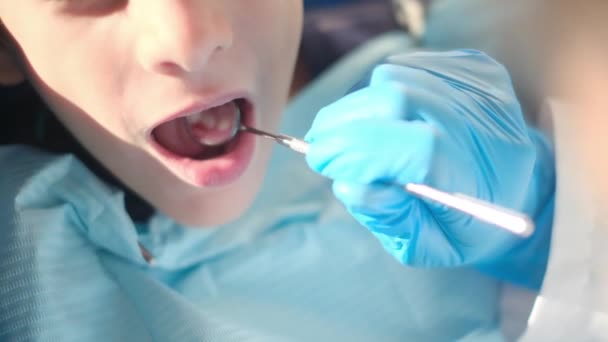 zubař vyšetřující chlapecké zuby zubním nářadím  - Záběry, video