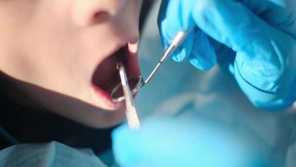dentista esaminando i denti del ragazzo con strumenti odontoiatrici  - Filmati, video