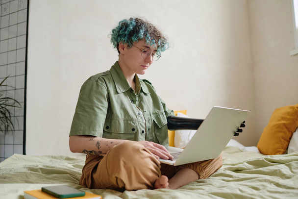 Ernste junge Frau mit Armprothese arbeitet von zu Hause aus - Foto, Bild