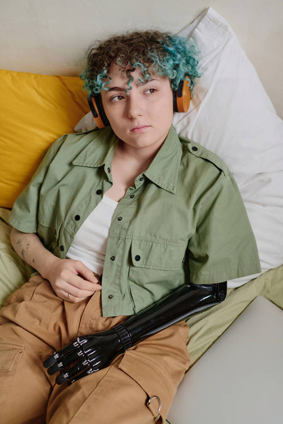 Retrato de chica pensativa con el pelo rizado verde escuchando podcast en auriculares - Foto, Imagen