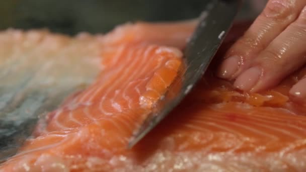 Lo chef taglia un filetto di pesce rosso fresco con un coltello. Cucinare carne cruda di salmone per bistecca al rallentatore vista da vicino. Sale di pesce rosso di alta qualità - Filmati, video