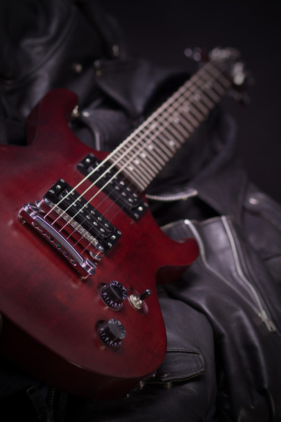 Elektrische gitaar liegen over black leather jackets - Foto, afbeelding