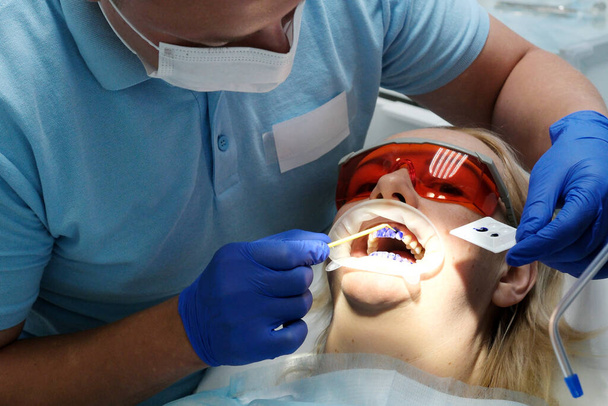 O dentista examina a condição de dentes com a ajuda de instrumentos médicos em pacientes menina. Recepção primária. Clínica dentária. Saúde. Foto de alta qualidade - Foto, Imagem