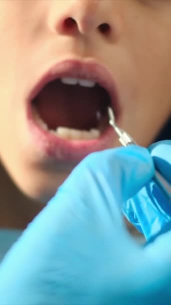 стоматолог осматривает зубы мальчика с помощью стоматологических инструментов  - Кадры, видео
