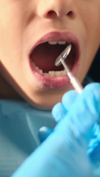 стоматолог вивчає зуби хлопчика за допомогою інструментів стоматології  - Кадри, відео