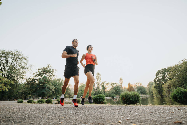 Подходящая пара мотивирует друг друга во время пробежки в парке. - Фото, изображение