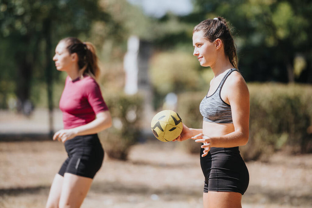 Sopii nuorille naisille pelaa ja pitää hauskaa aurinkoisessa puistossa, heittää rugby pallo. Ulkona harjoitus luonnossa. Urheilu ja virkistys. - Valokuva, kuva