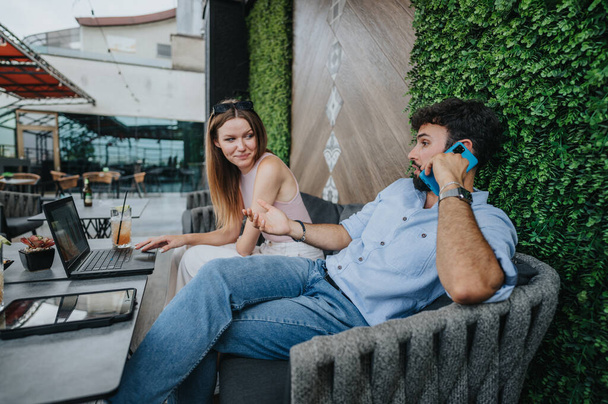 Young business couple discusses ideas for profit growth and market expansion in a city coffee bar. Corporate-minded entrepreneurs embrace remote work and e-commerce. - Photo, Image