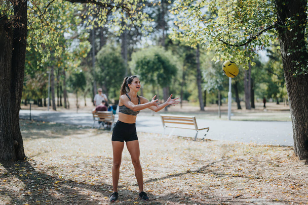 Aktywne dziewczyny ćwiczące na świeżym powietrzu w parku miejskim, rzucające amerykańską piłkę nożną. Cieszą się słoneczny dzień razem, pokazując swoje umiejętności sportowe i zabawy. - Zdjęcie, obraz
