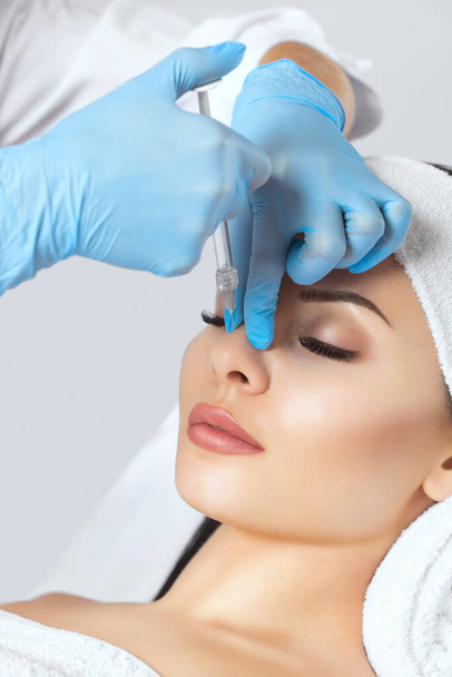 Lekarz kosmetolog sprawia, że ukłucie w nos poprawia garb pięknej kobiety w salonie piękności. Kosmetologia pielęgnacji skóry. - Zdjęcie, obraz
