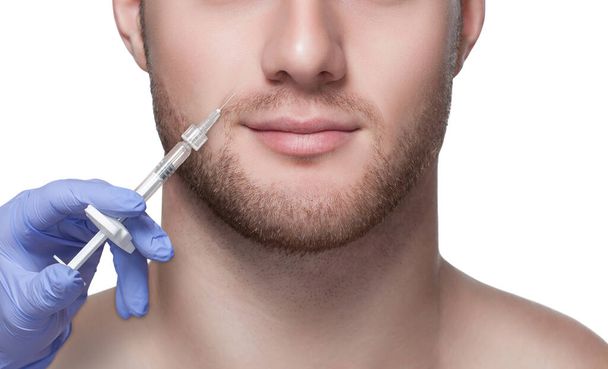 Cosmetologia maschile. Estetista rende un uomo una procedura di iniezione di ringiovanimento sul suo viso. - Foto, immagini