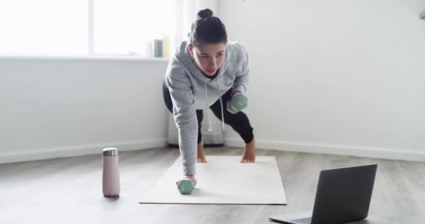 Vrouw, halter en push-ups voor oefening met laptop, ademhaling en yoga mat in de woonkamer van huis. Persoon, gewichten en workout voor fitness, wellness en lichaamsbeweging op de vloer met technologie. - Video