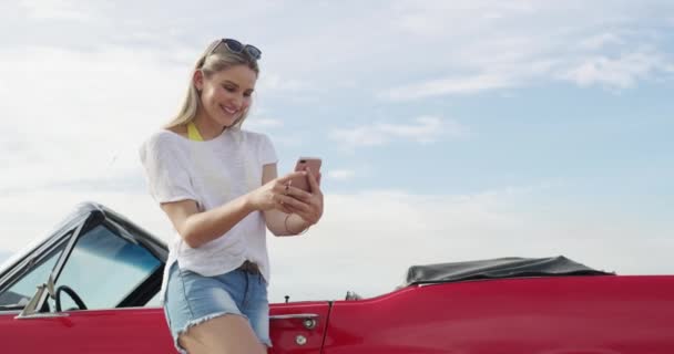 Adventure, phone and woman by a car for road trip, vacation or weekend holiday in the coast. Transport, travel and young female person from Australia networking on cellphone by a new luxury vehicle - Footage, Video