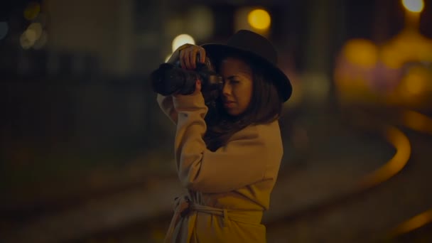 Młoda kobieta fotograf zrobić zdjęcia na ulicy miejskiej w świetle nocnym - Materiał filmowy, wideo