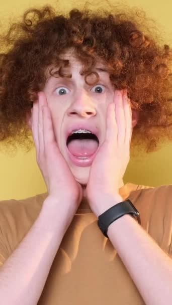 Portrait of surprised curly man on yellow background. Vertical video. - Footage, Video