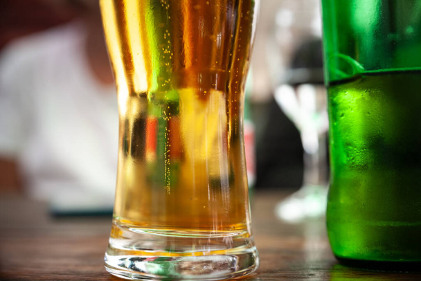 Επιλεκτική θολούρα σε κοντινό πλάνο σε κούπα μπύρας που περιέχει ελαφριά μπύρα, τύπου pilsner / lager, σερβιρισμένη σε κανονικό ποτήρι μεγέθους μπύρας. - Φωτογραφία, εικόνα