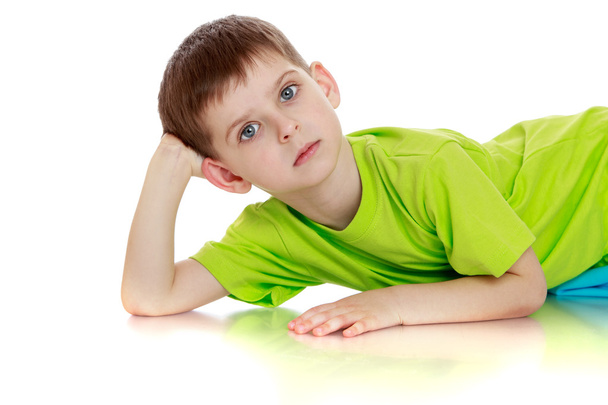 Little boy in green t-shirt lying on the floor. - Foto, afbeelding