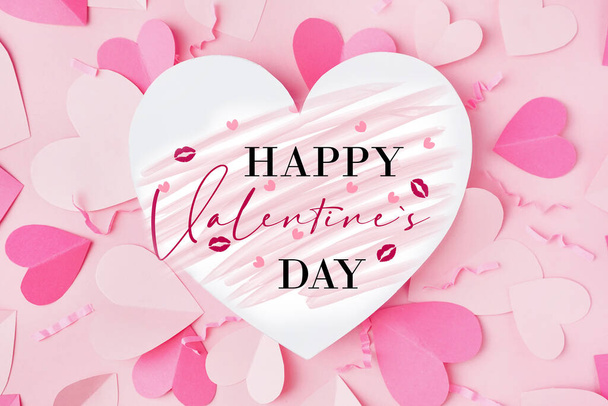 Mooie wenskaart voor Valentijnsdag met papieren hartjes op roze achtergrond - Foto, afbeelding