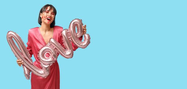 Sevgililer Günü için yaratıcı makyajı olan şık genç bir kadın ve mavi arka planda aşk kelimesi şeklinde bir balon. - Fotoğraf, Görsel