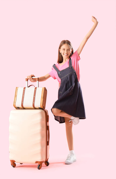 Happy little girl with suitcases on pink background - Photo, Image