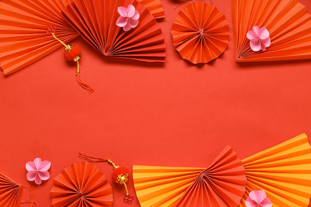 Rajongók gyönyörű virágok és lámpások piros háttérrel. Kínai Újévi ünnepség - Fotó, kép