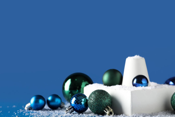 Dekorative Stände mit verschiedenen Weihnachtskugeln und Schnee auf blauem Hintergrund - Foto, Bild