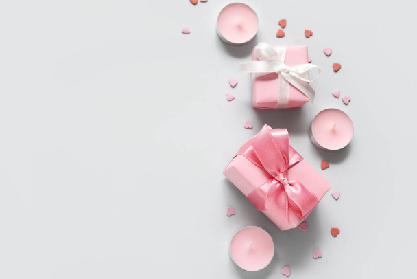 Rózsaszín ajándékdobozok, szívek és gyertyák szürke háttérrel. Valentin-napi ünneplés - Fotó, kép