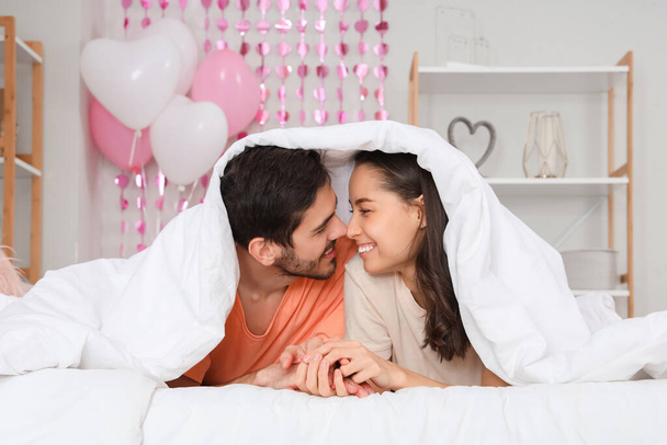 Felice giovane coppia toccando nasi sotto coperta in camera da letto a San Valentino - Foto, immagini